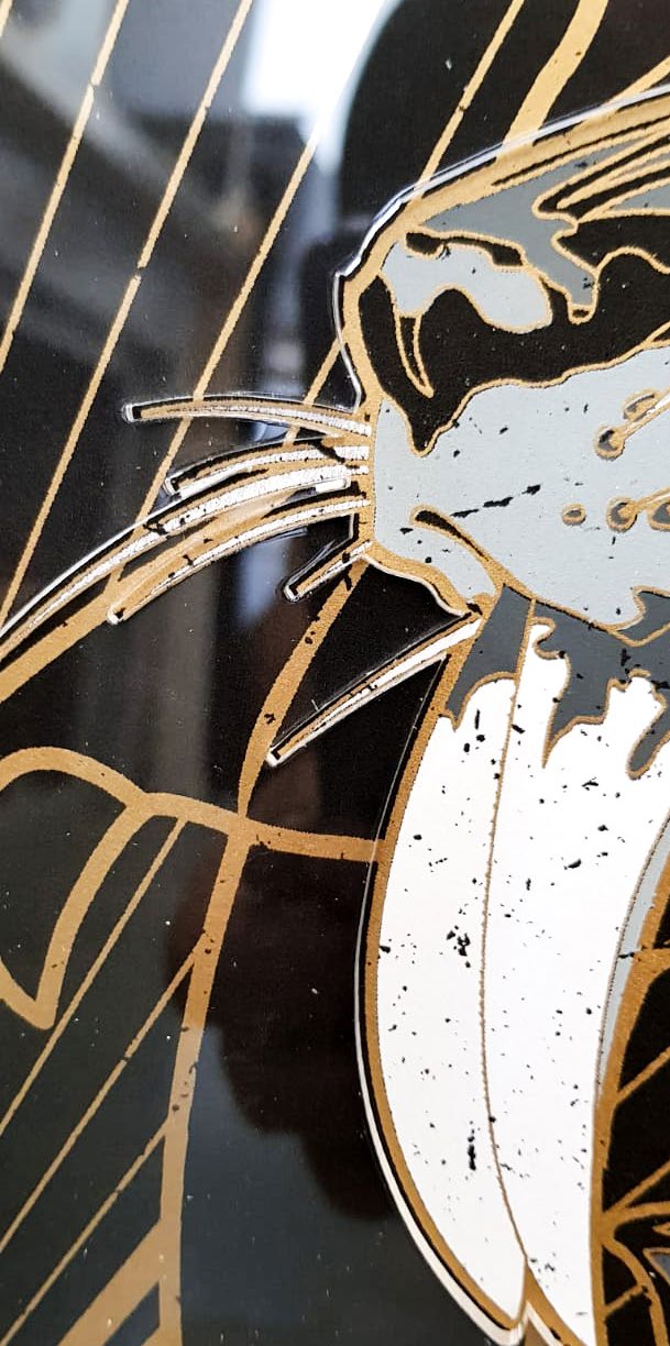 Detail des fertigen Smilodon-Siebdrucks mit goldenen Linien, körniger Farbfläche und geöffneter Acrylabdeckung.